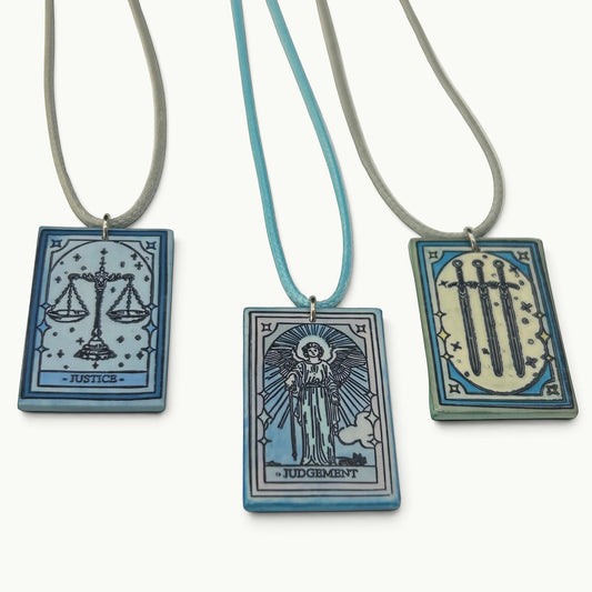 DTB Alchemy handmade matte white polymer clay tarot card necklaces featuring Justice, Judgement, and Three of Swords.